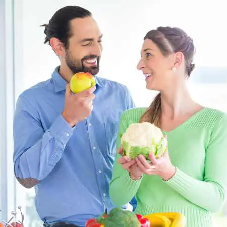 man and woman holding vegetables