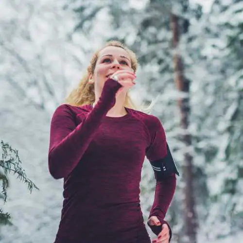 model wearing maroon compression shirt running in the snow. running shirt buying guide
