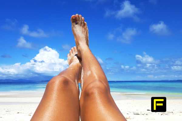 woman sunbathing at beach with legs in the air on a sunny day.