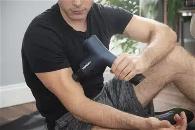Male athlete using EKRIN Athletics massage gun. Post workout, Pre workout.