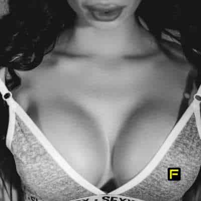 Black and white close-up of a woman's bust in a low-cut top, emphasizing cleavage and skin smoothness. This image represents beauty, confidence, and bust enhancement, suitable for content related to bust firming and self-care.