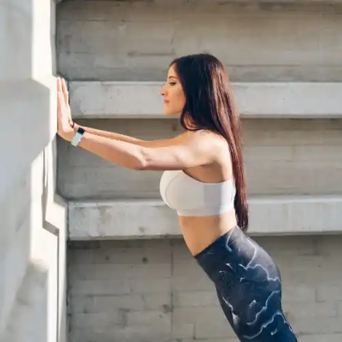 5 Best Low Impact Exercises for Seniors to Stay Active and Strong 3 Woman performing wall pushups, which is great for building strength without floor workout.